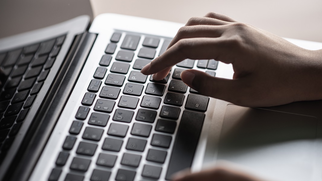 Primo piano di una mano che digita su una tastiera del laptop