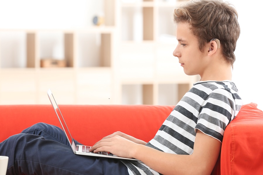 Ragazzo al pc con un apparecchio acustico