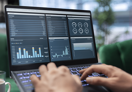 Immagine di una persona che scrive al Pc, grafici e indicatori di vario tipo sullo schermo