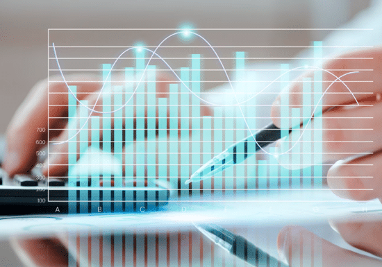 Primo piano di un grafico con diversi valori, persona che scrive ad un pc sullo sfondo