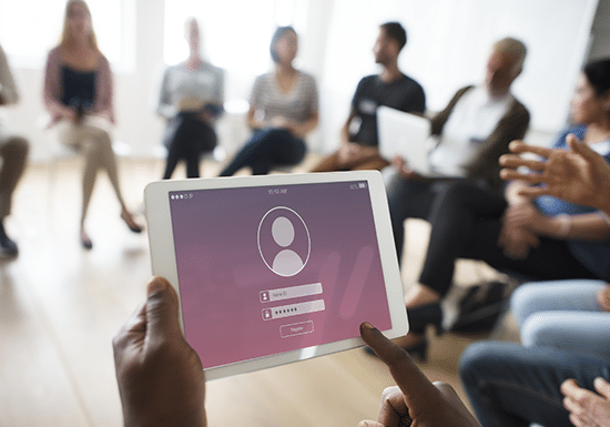 Gruppo di persone sedute in cerchio, un tablet in primo piano