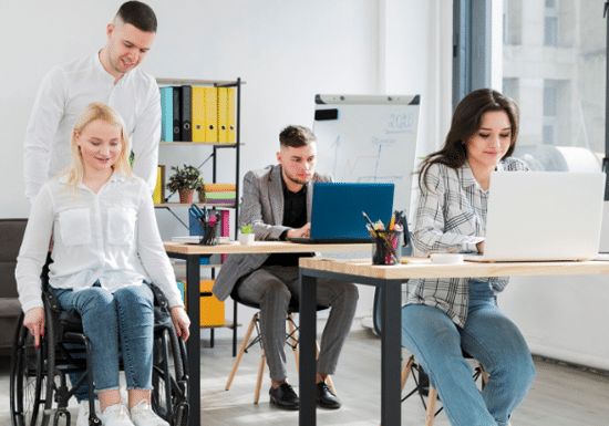 Gruppo di persone giovani, due sedute a delle scrivanie e una in carrozzina